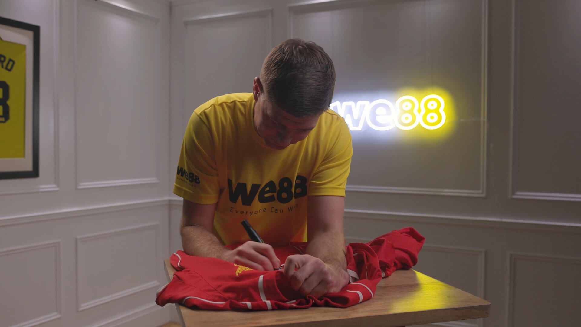 WE88 26/27 Global Brand Ambassador Steven Gerrard signing a red football jersey during an exclusive behind-the-scenes session